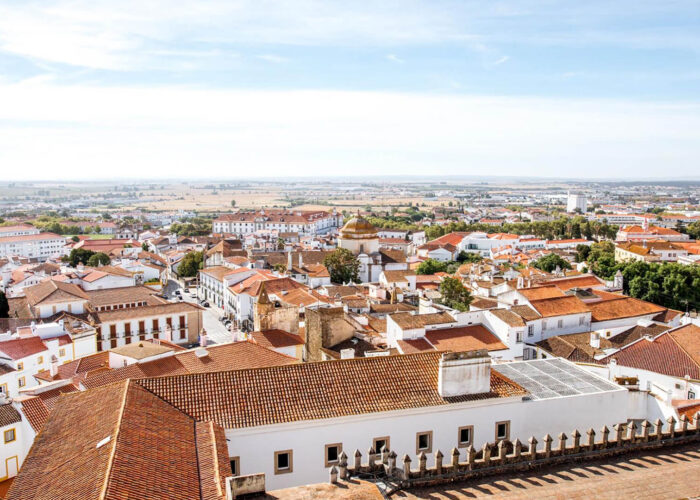 A panoramic view of a town with white buildings and terracotta roofs, surrounded by fields under a blue sky—one of the hidden gems Portugal offers to those seeking underrated places in Portugal.