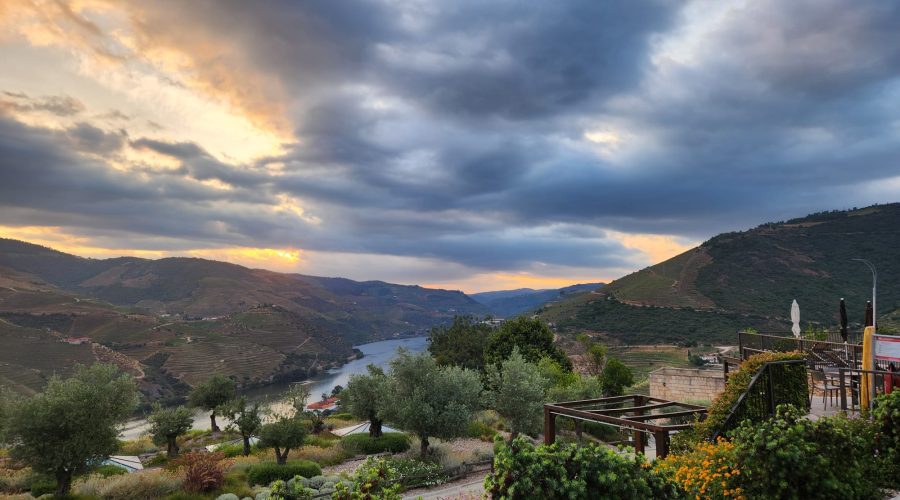 A river winds through a valley with lush hills and gardens in the foreground, under a dramatic cloudy sky at sunset—a perfect scene to discover on your 8-Day Portugal Tour. A river winds through a valley with lush hills and gardens in the foreground, under a dramatic cloudy sky at sunset—a perfect scene to discover on your 8-Day Portugal Tour.